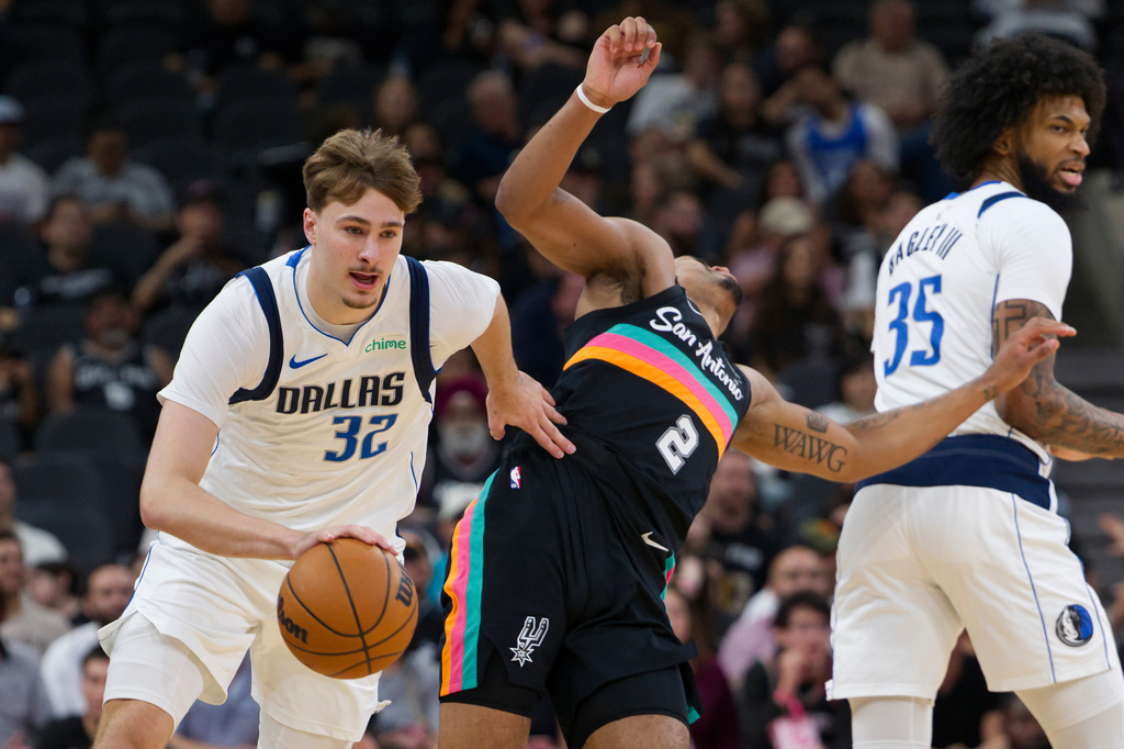 Dallas Mavericks guard Cooper Flagg (32) collides with San Antonio Spurs guard Dylan Harper (2) during the first half of an NBA basketball game, Friday, April 10, 2026, in San Antonio. (AP Photo/Darren Abate)