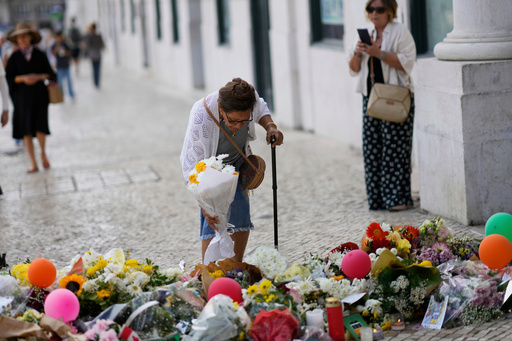 FILE - An elderly woman places a bouquet of flowers at a tribute to those that perished in the Gloria funicular, a tourist streetcar that derailed and crashed, in Lisbon, Sept. 6, 2025. (AP Photo/Armando Franca, File) FILE - An elderly woman places a bouquet of flowers at a tribute to those that perished in the Gloria funicular, a tourist streetcar that derailed and crashed, in Lisbon, Sept. 6, 2025. (AP Photo/Armando Franca, File)