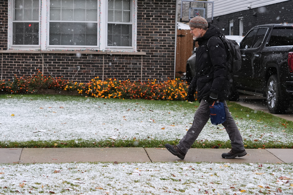 Pedestrian walks on the sidewalk during a snowy day in Skokie, Ill., Sunday, Nov. 9, 2025. (AP Photo/Nam Y. Huh)