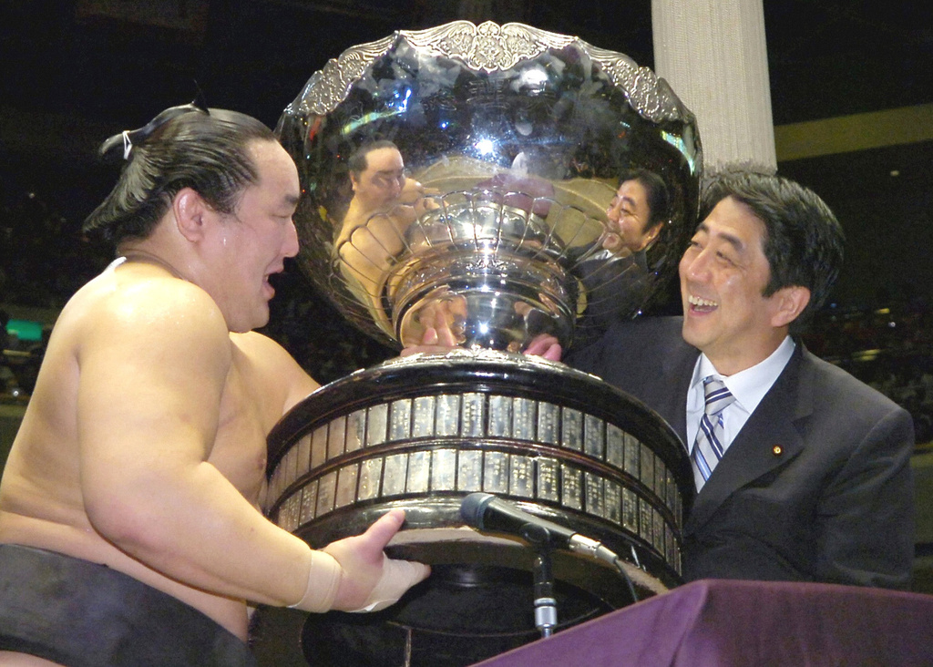 FILE - Grand champion Asashoryu of Mongolia, left, receives the Prime Minister's Cup from Chief Cabinet Secretary and soon-to-be Premier Shinzo Abe at Tokyo's Ryogoku Sumo Arena on Sept. 24, 2006. (Kyodo News via AP, File)