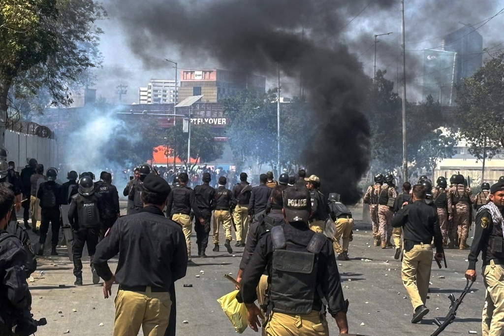 Police officers chase Shiite Muslims blocking a road and set on fire tires during a protest over the killing of Iranian Supreme Leader Ayatollah Ali Khamenei, in Karachi, Pakistan, Sunday, March 1, 2026. (AP Photo/Muhammad Farooq)