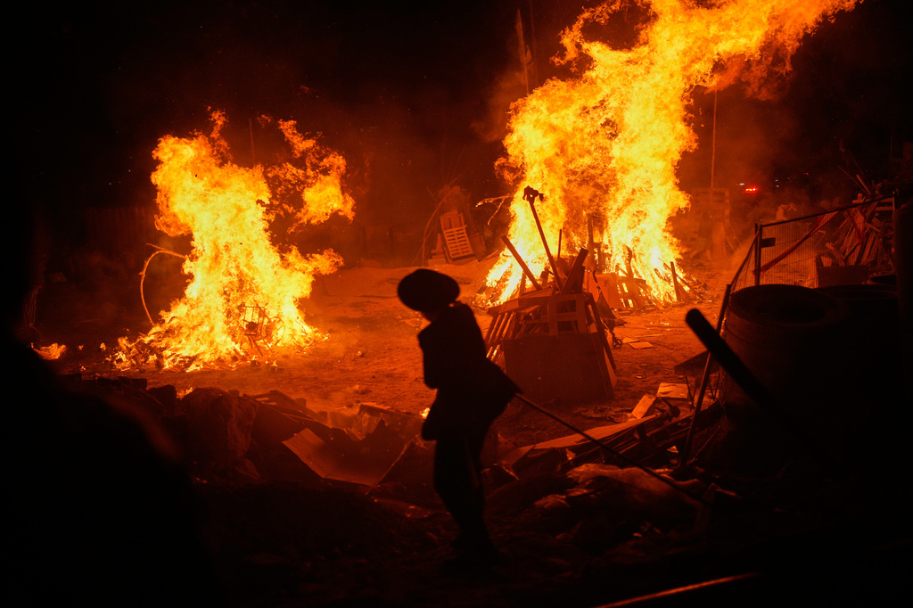 An ultra-Orthodox Jewish youth stands next to bonfires during Lag BaOmer, a holiday traditionally celebrated with bonfires, music, and gatherings, in Jerusalem, Monday, May 4, 2026. (AP Photo/Ohad Zwigenberg)