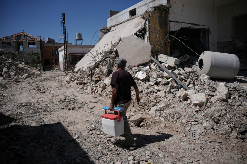 Mohammed Sobeih returns to his home, destroyed during the Israeli military operation, carrying a cooler in Zawtar al-Gharbieh, Lebanon, Tuesday, July 28, 2026. (AP Photo/Hassan Ammar)