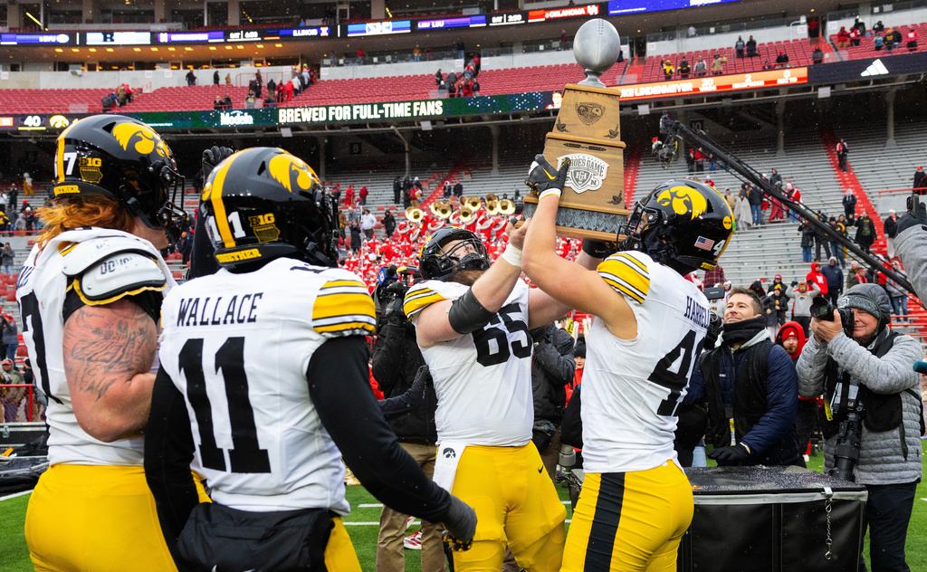 Iowa offensive lineman Logan Jones (65) and linebacker Jaden Harrell (41) hoist the Heroes Game Trophy following their win against Nebraska during the second half of an NCAA college football game Friday, Nov. 28, 2025, in Lincoln, Neb. (AP Photo/Rebecca S. Gratz)