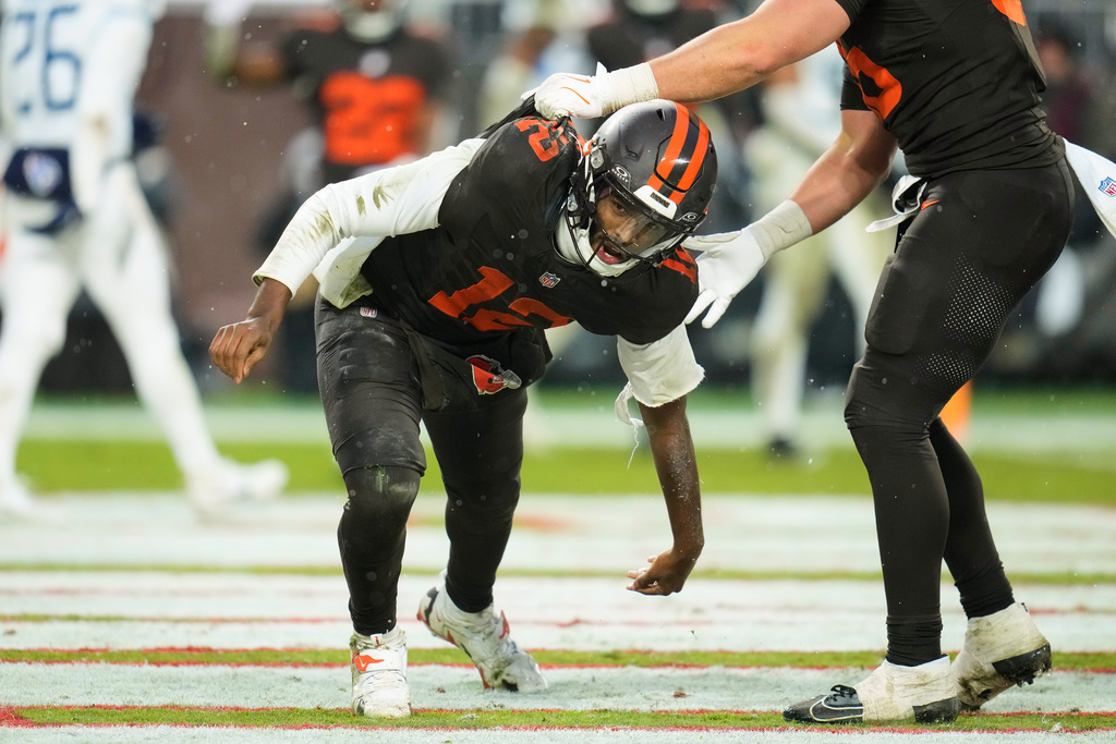 Cleveland Browns quarterback Shedeur Sanders (12) gets help from a teammate after scoring a touchdown on a run in the second half of an NFL football game against the Tennessee Titans in Cleveland, Sunday, Dec. 7, 2025. (AP Photo/Sue Ogrocki)