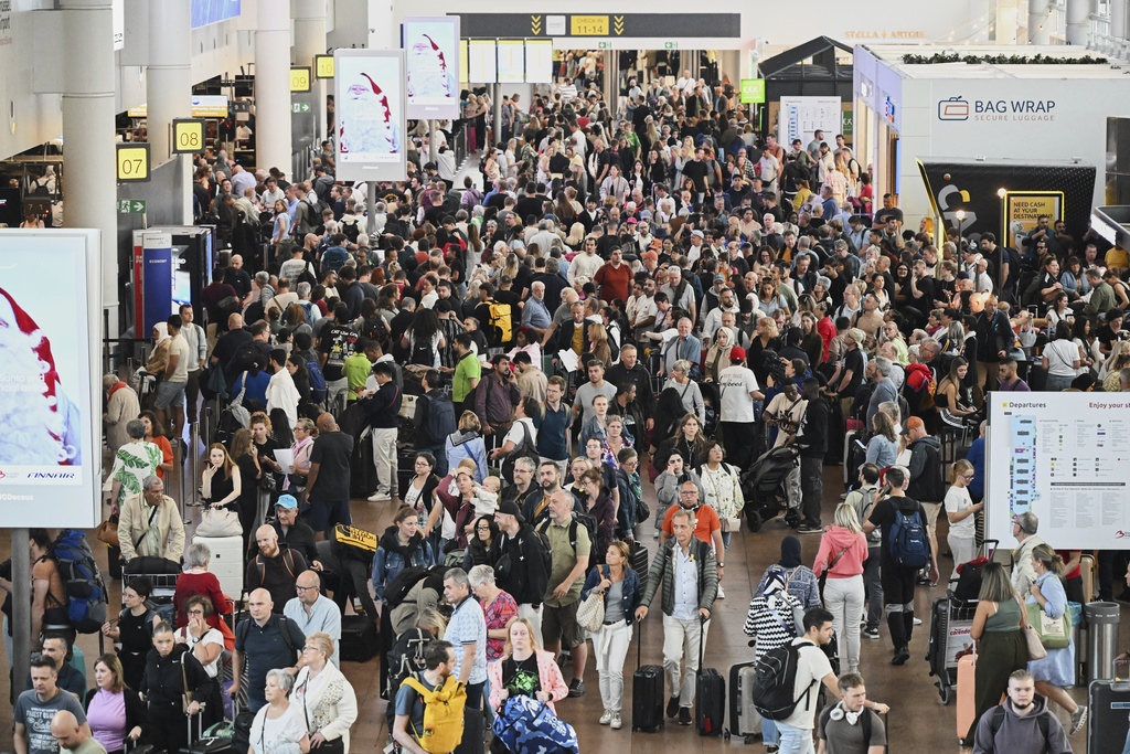 People walk by a departures board after a cyber attack caused delays at Brussels International Airport in Zaventem, Belgium, Saturday, Sept. 20, 2025. (AP Photo/Harry Nakos)