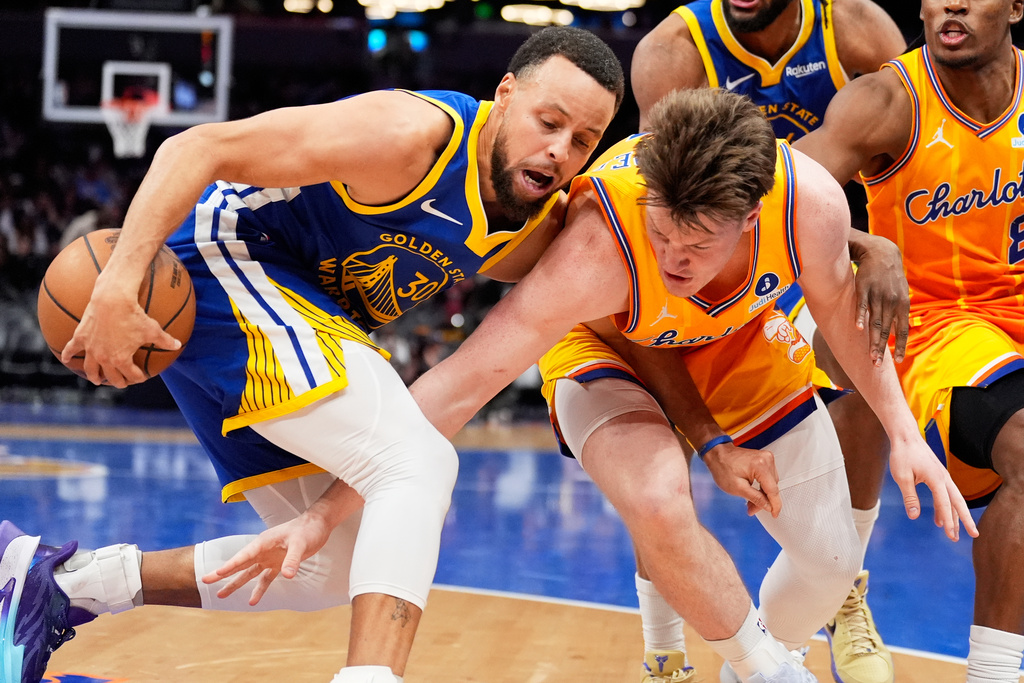 Golden State Warriors guard Stephen Curry vies for the ball with Charlotte Hornets guard Kon Knueppel during the second half of an NBA basketball game, Wednesday, Dec. 31, 2025, in Charlotte, N.C. (AP Photo/Chris Carlson)