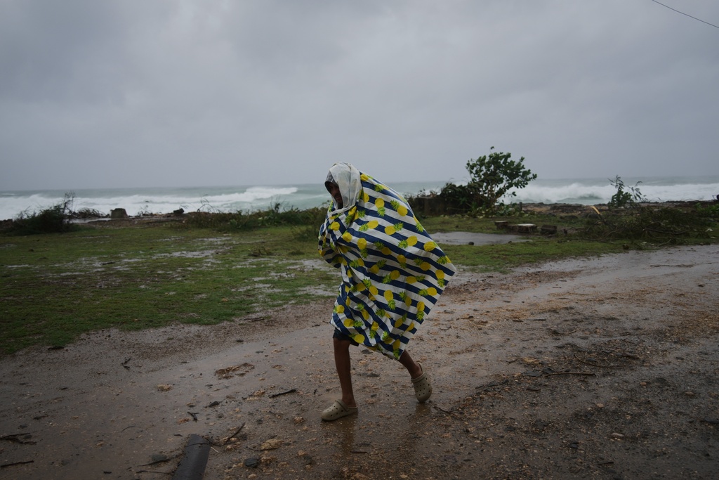 A man walks in the rain before the arrival of Hurricane Melissa in Canizo, a village in Santiago de Cuba, Tuesday, Oct. 28, 2025. (AP Photo/Ramón Espinosa)