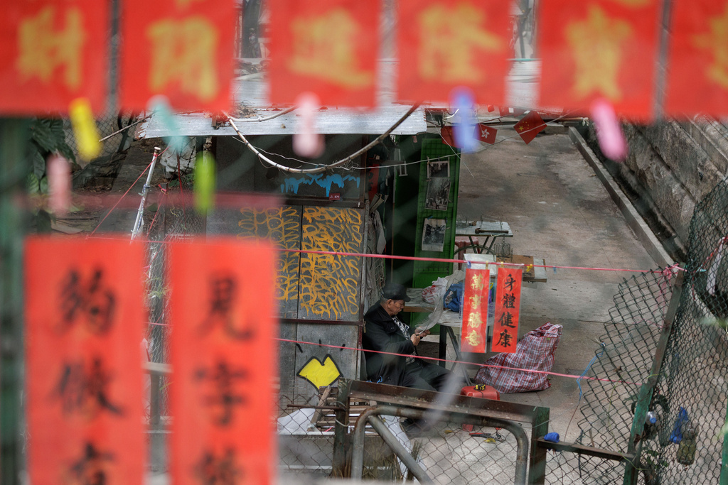 A man is seen through hand written Lunar New Year couplets hanging in Hong Kong, Monday, Feb. 9, 2026. (AP Photo/May James)