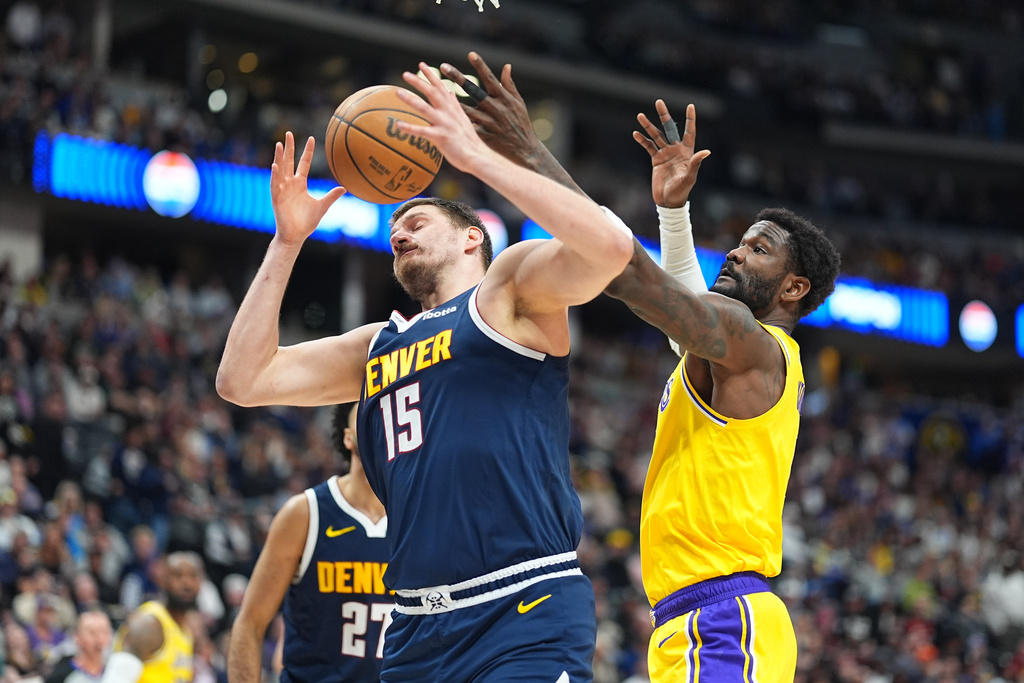 Denver Nuggets center Nikola Jokić, left, fights for control of a rebound with Los Angeles Lakers center Deandre Ayton in the first half of an NBA basketball game Thursday, March 5, 2026, in Denver. (AP Photo/David Zalubowski)