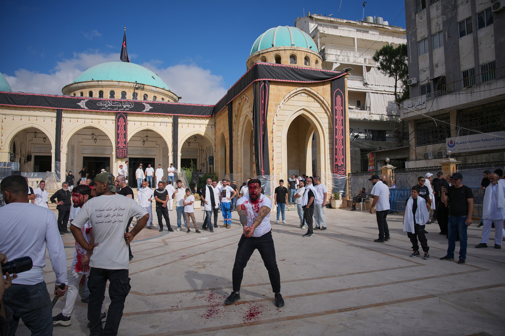 A Lebanese Shiite strikes his head with a sword, bleeding from self-inflicted wounds, during Ashoura, when Shiites commemorate the martyrdom of Imam Hussein, the grandson of the Prophet Muhammad, in In Nabatiyeh, southern Lebanon, Friday, June 26, 2026. (AP Photo/Hassan Ammar)