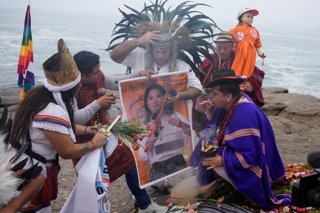 A shaman performs a ritual holding a poster of presidential candidate Keiko Fujimori on Herradura beach in Lima, Peru, Monday, June 1, 2026, ahead of a presidential runoff election. (AP Photo/Martin Mejia)
