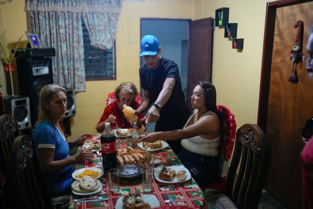 Mariela Gómez, right, and her partner Abraham Castro, a Venezuelan migrant couple, sit for Christmas dinner at Castro's parents' home in Maracay, Venezuela, early Thursday, Dec. 25, 2025. The couple abandoned their journey to the United States and returned home from Mexico by land and sea following President Donald Trump's immigration crackdown. (AP Photo/Matias Delacroix)