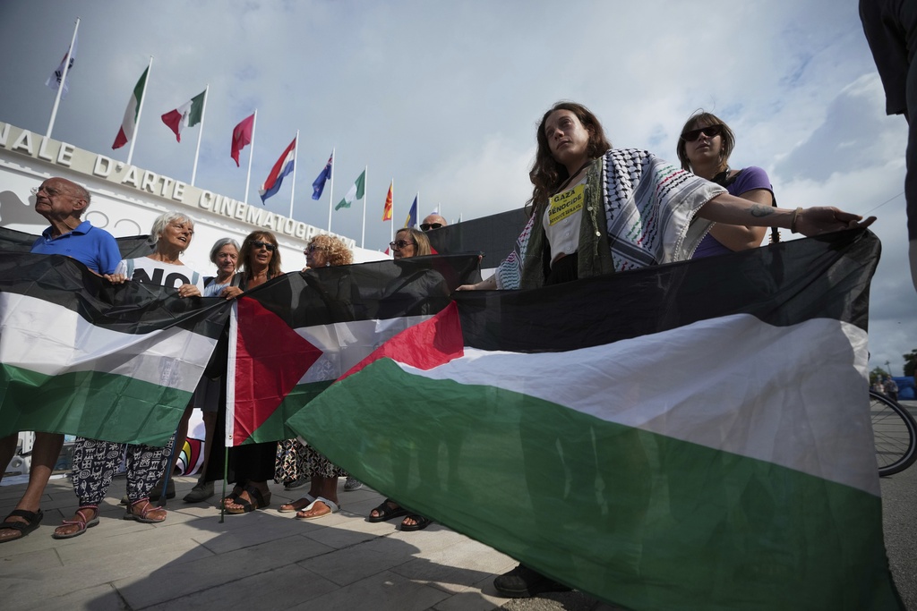 Pro Palestine demonstrators hold Palestinian flags during a press conference in front of the red carpet to announce a demonstration on Saturday, Aug. 30 during the 82nd edition of the Venice Film Festival in Venice, Italy, on Wednesday, Aug. 27, 2025. (Photo by Alessandra Tarantino/Invision/AP)