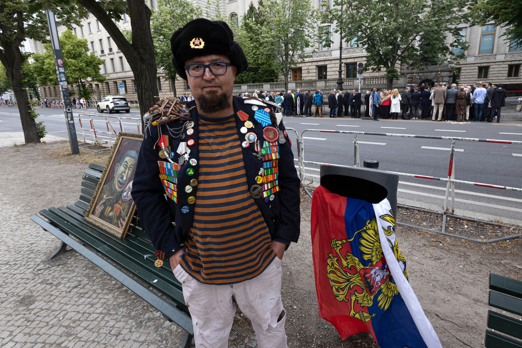 A man identified by Polish media as Robert Kuzovkov and by prosecutors as Robert K., in accordance with Polish privacy law, who they said was an artist who used the pseudonym Semyon Skrepetsky, poses for a photo with one of his paintings near the Russian Embassy in Berlin, Germany, on Friday, June 12, 2026, four days before Polish authorities said he was shot and killed in Biala Podlaska, Poland. (Vasily Krestyaninov/SOTA via AP)