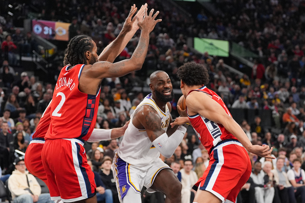 Los Angeles Lakers forward Lebron James, center, is defended by Los Angeles Clippers forward Kawhi Leonard, left, and guard Kobe Sanders during the first half of an NBA basketball game Saturday, Dec. 20, 2025, in Inglewood, Calif. (AP Photo/Jae C. Hong)