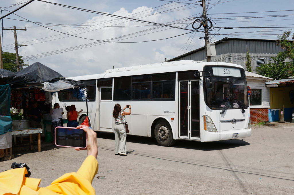 Journalists take images of a bus transporting migrants deported from the United States following their arrival at the Ramón Villeda Morales Airport in San Pedro Sula, Honduras, Thursday, Aug. 20, 2026. (AP Photo/Delmer Martinez)