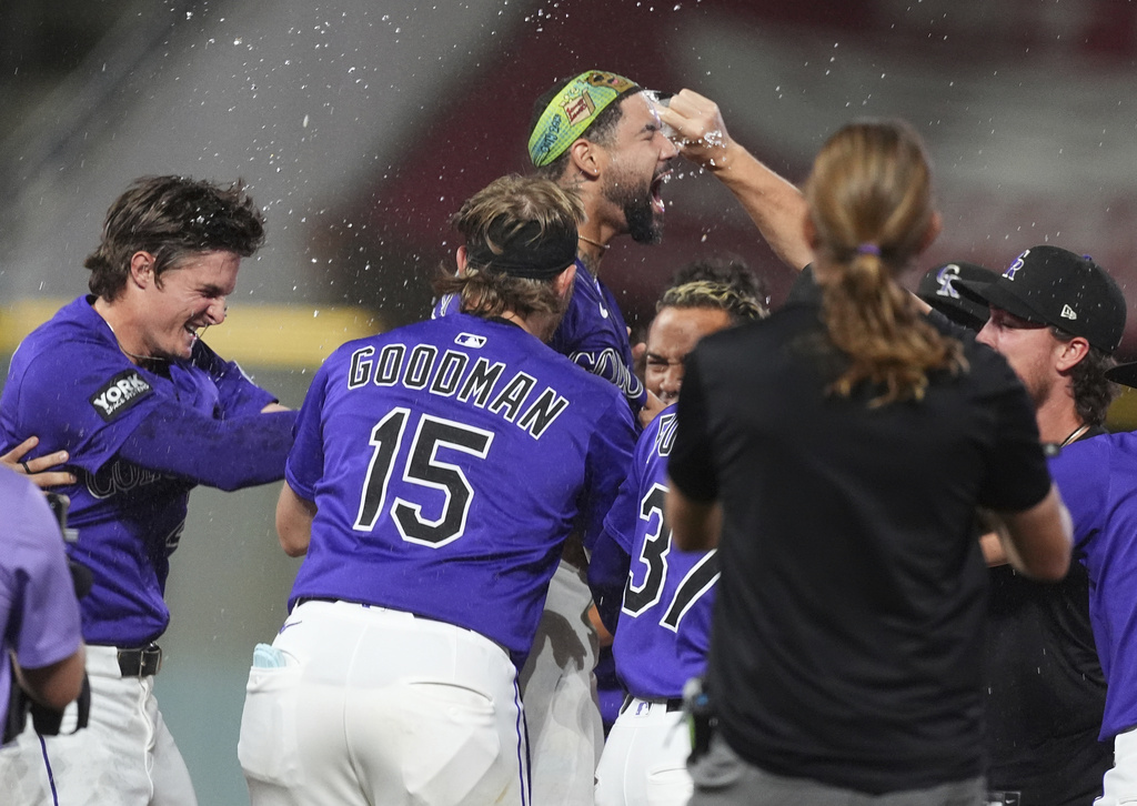 Teammates surround Colorado Rockies' Warming Bernabel, center top, to celebrate after his walk-off RBI single off Los Angeles Dodgers relief pitcher Justin Wrobleski in the ninth inning of a baseball game Monday, Aug. 18, 2025, in Denver. (AP Photo/David Zalubowski)