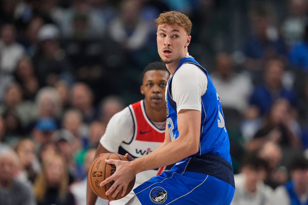 Dallas Mavericks forward Cooper Flagg looks to make a pass as Washington Wizards' Bub Carrington, rear, defends in the first half of an NBA basketball game, Friday, Oct. 24, 2025, in Dallas. (AP Photo/Tony Gutierrez)