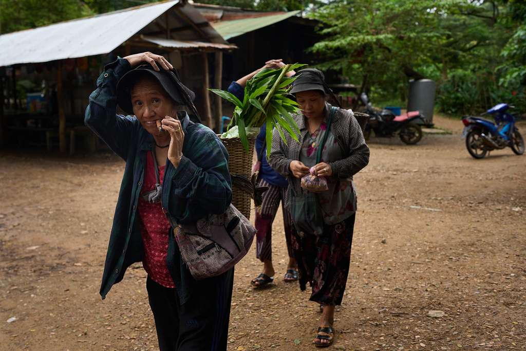 A woman smokes tobacco after returning from foraging for food outside their refugee camp in the Tak province of Thailand, Tuesday, Aug. 26, 2025. (AP Photo/Bram Janssen)