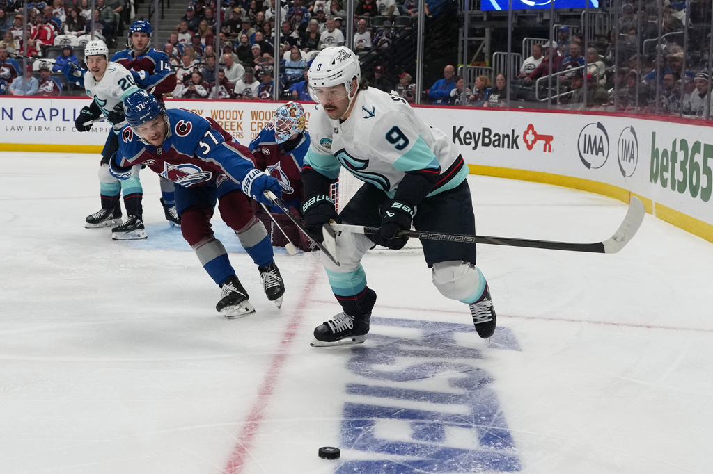 Seattle Kraken center Chandler Stephenson (9) pursues the puck with Colorado Avalanche defenseman Nick Blankenburg (37) in the second period of an NHL hockey game Thursday, April 16, 2026, in Denver. (AP Photo/David Zalubowski)