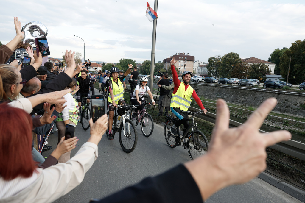 People welcome a group of university students at the end of their cycling tour of the Balkan country ahead of an early election next month challenging populist President Aleksandar Vucic, in Kragujevac, Serbia, Saturday, Sept. 26, 2026. (AP Photo/Marko Drobnjakovic)