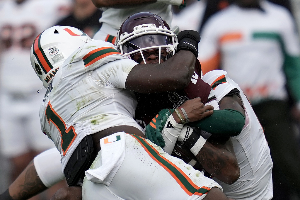 Texas A&M quarterback Marcel Reed (10) is tackled after a short run by Miami linebacker Mohamed Toure (1) and defensive back Keionte Scott (0) during the first quarter in the first round of the College Football Playoff Saturday, Dec. 20, 2025, in College Station, Texas. (AP Photo/Sam Craft)