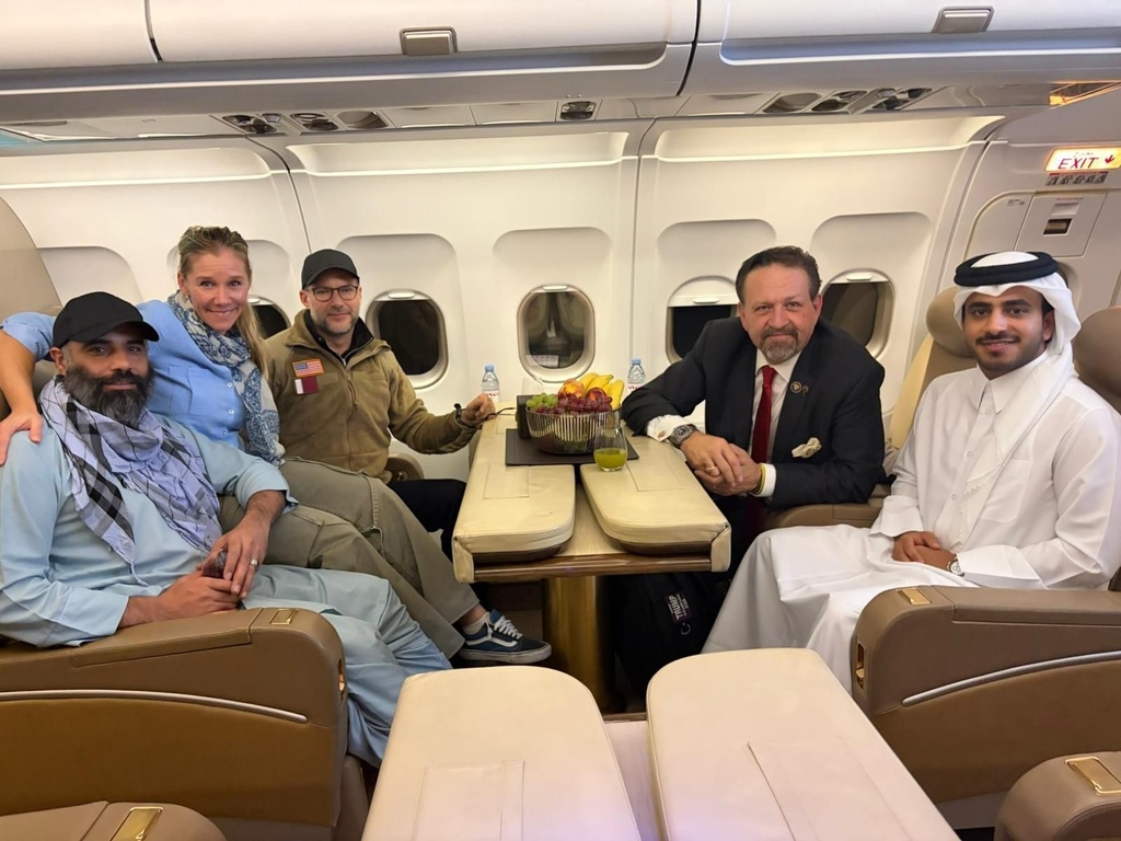 In this photo released by Qatar's Foreign Ministry, U.S. citizen Amir Amiri, left, poses next to an unidentified woman, aboard a plane in Kabul, Afghanistan, on Sunday, Sept. 28, 2025, after being released from an Afghan prison. With him, from right, are a Qatari diplomat, Deputy Assistant to the U.S. President Sebastian Gorka, and U.S. Special Envoy for Hostage Response Adam Boehler.(Qatar Foreign Ministry via AP)