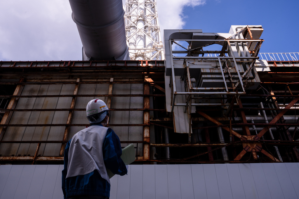 An employee stands next to the Radioactive Waste Treatment Building at the Fukushima Daiichi nuclear power plant, operated by Tokyo Electric Power Company (TEPCO), in Okuma, Fukushima Prefecture, Thursday, Feb. 12, 2026. (AP Photo/Louise Delmotte)