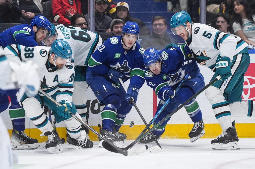 Vancouver Canucks' Conor Garland (8), Liam Ohgren (92) and Filip Chytil (72) vie for the puck against San Jose Sharks' Vincent Desharnais (5), Mario Ferraro (38) and Zack Ostapchuk (63) during the third period of an NHL hockey game, in Vancouver, British Columbia, Tuesday, Jan. 27, 2026. (Darryl Dyck/The Canadian Press via AP)