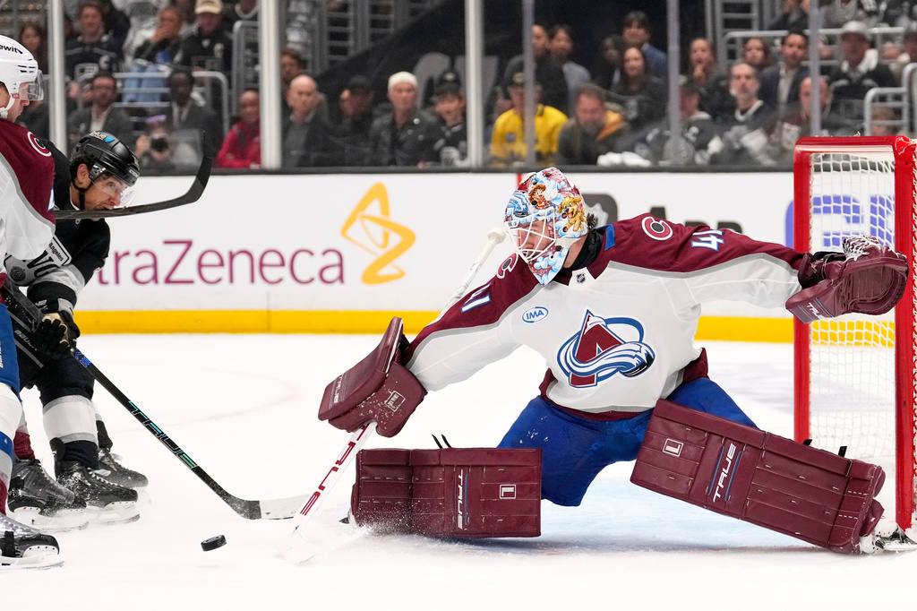 Los Angeles Kings left wing Trevor Moore, center, is hit in the mouth by Colorado Avalanche defenseman Josh Manson, left, as he scores on goaltender Scott Wedgewood, right, during the second period of Game 3 in the first round of the NHL hockey Stanley Cup playoffs Thursday, April 23, 2026, in Los Angeles. (AP Photo/Mark J. Terrill)