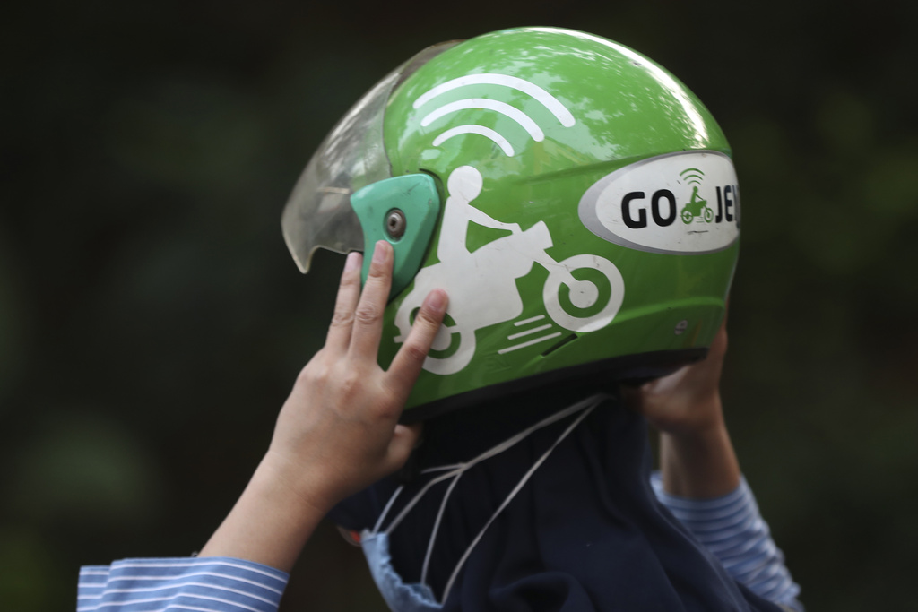 FILE- A woman holds a Gojek helmet after arriving at a station in Jakarta, Indonesia, May 17, 2021. (AP Photo/Achmad Ibrahim, File)