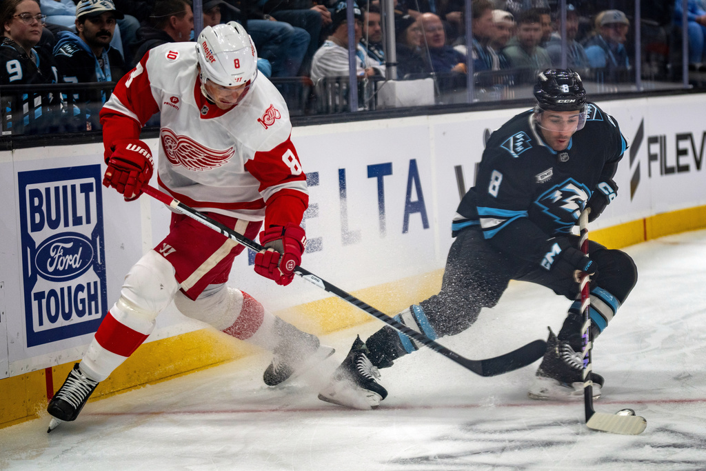 Utah Mammoth center Nick Schmaltz (8) grabs the puck as Detroit Red Wings defenseman Ben Chiarot (8) defends during the first period of an NHL hockey game Wednesday, Feb. 4, 2026, in Salt Lake City. (AP Photo/Rick Egan)