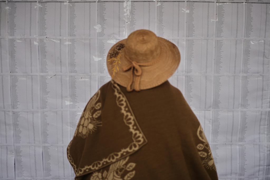 A person checks the rolls during a presidential runoff election in El Alto, Bolivia, Sunday, Oct. 19, 2025. (AP Photo/Ivan Valencia)