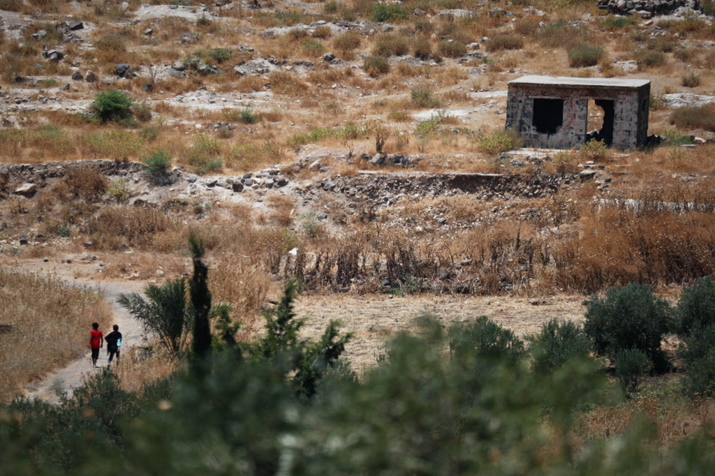 Two boys walk along a road near a damaged building in the village of Abdin, Daraa province, Syria, Monday, June 29, 2026, after local residents said Israeli forces carried out an incursion into the area a day earlier. (AP Photo/Omar Sanadiki)