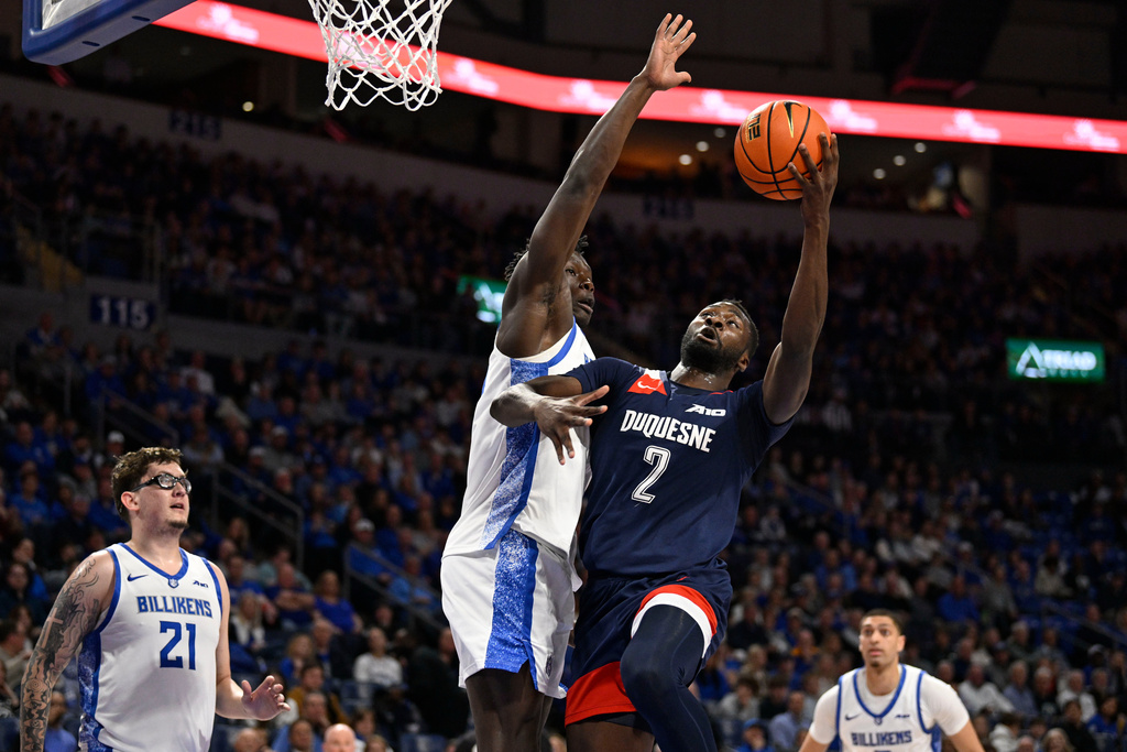 Duquesne's David Dixon (2) goes for a lay up as Saint Louis Billikens forward Paul Otieno, center, defends during the first half of an NCAA college basketball game Saturday, Feb. 28, 2026, in St. Louis. (AP Photo/Jeff Le)