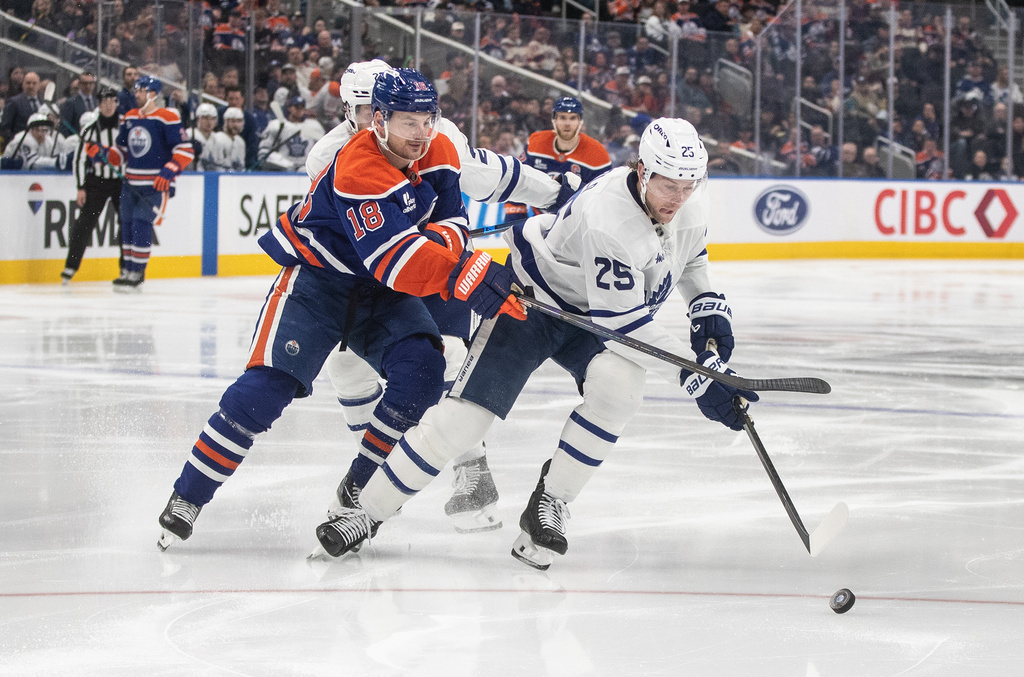 Toronto Maple Leafs' Brandon Carlo (25) and Edmonton Oilers' Zach Hyman (18) battle for the puck during the second period of an NHL game in Edmonton, Tuesday, Feb. 3, 2026. (Jason Franson/The Canadian Press via AP)