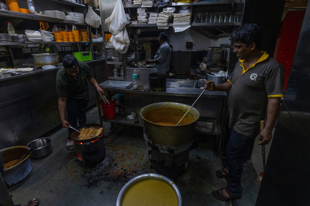 FILE- Cooks at a restaurant prepare meals over a charcoal stove following a shortage of liquefied petroleum gas in Mumbai, India, Wednesday, March 11, 2026. (AP Photo/Rafiq Maqbool, File)