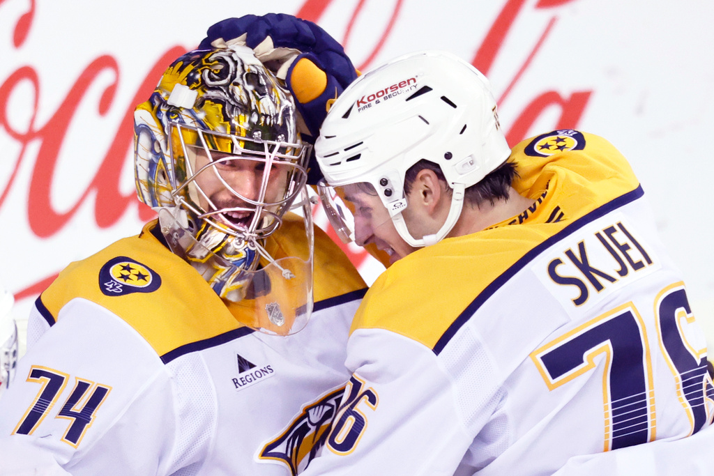 Nashville Predators goalie Juuse Saros, left, is congratulated by Brady Skjei, right, after their team defeated the Calgary Flames in NHL hockey game action in Calgary, Alberta, Saturday, Jan. 3, 2026. (Larry MacDougal/The Canadian Press via AP)