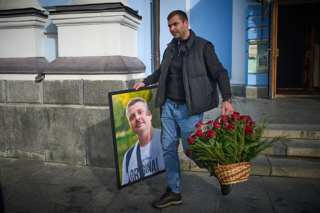 A man caries a photo of cameraman Yevhen Karmazin, who was killed together with corespondent Olena Hubanova, who worked under the pseudonym Alyona Gramova on Thursday, Oct. 23, when a Russian Lancet drone hit their vehicle in Ukraine's Kramatorsk around 20 kilometres from the front line, after funeral service at St. Michael Monastery in Kyiv, Ukraine, Monday, Oct. 27, 2025. (AP Photo/Efrem Lukatsky)