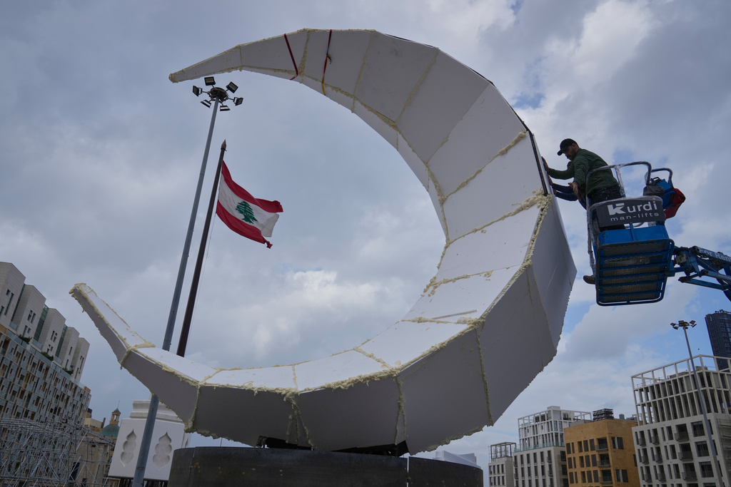 A worker sets a giant crescent-shaped decoration on the first day of the Muslim holy month of Ramadan in downtown Beirut, Lebanon, Wednesday, Feb. 18, 2026. (AP Photo/Hussein Malla)