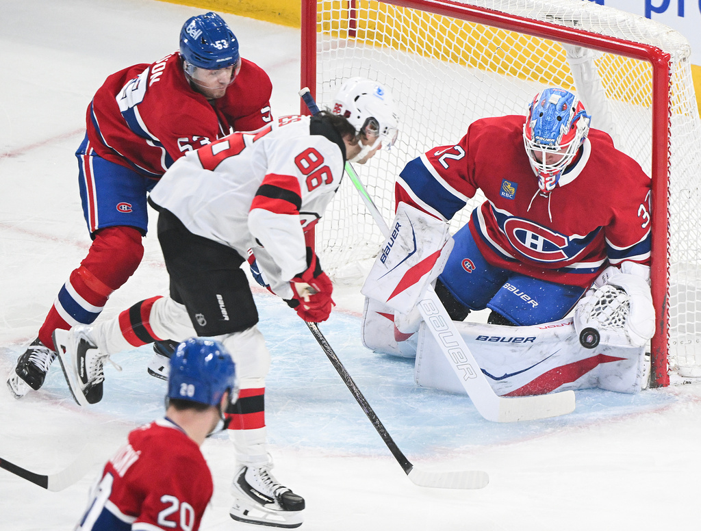 Montreal Canadiens' Noah Dobson (53) defends against New Jersey Devils' Jack Hughes (86) as he moves in on Canadiens goaltender Jacob Fowler (32) during first period of an NHL hockey game in Montreal, Sunday, April 5, 2026.(Graham Hughes/The Canadian Press via AP)