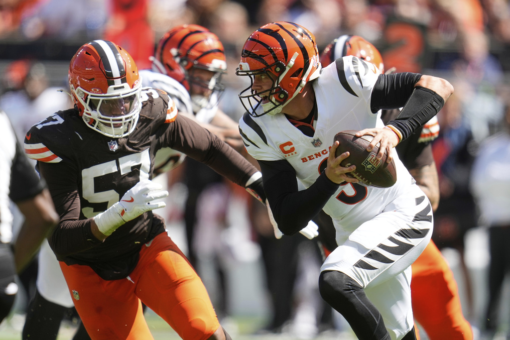 Cincinnati Bengals quarterback Joe Burrow (9) is chased by Cleveland Browns defensive end Isaiah McGuire (57) during the first half of an NFL football game Sunday, Sept. 7, 2025, in Cleveland. (AP Photo/Sue Ogrocki)