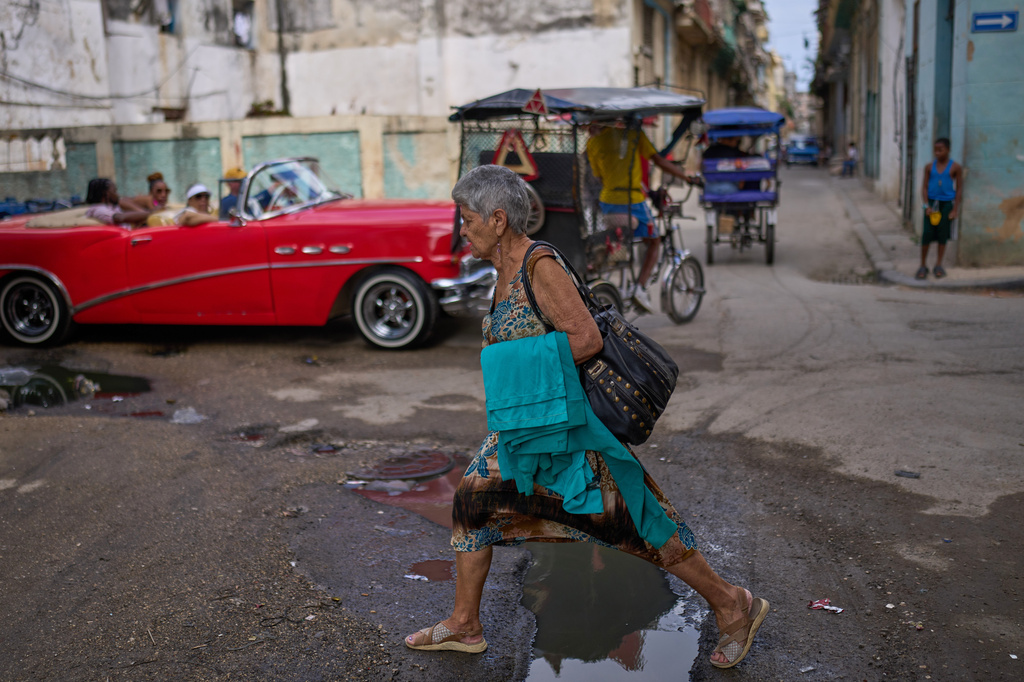 A woman steps over a puddle while walking through Old Havana, Cuba, Saturday, Feb. 15, 2025. (AP Photo/Ramon Espinosa)