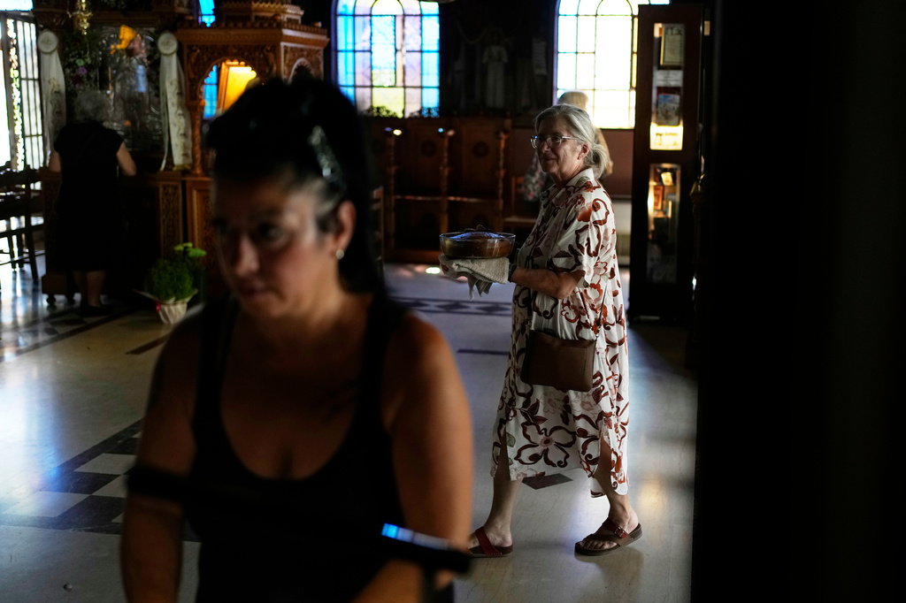 Maria Chanioti, 66, carries Fanouropita, an orange-flavored cake, to be blessed by a priest at the Church of St. Fanourios in Athens, Wednesday, Aug. 26, 2026. (AP Photo/Thanassis Stavrakis)