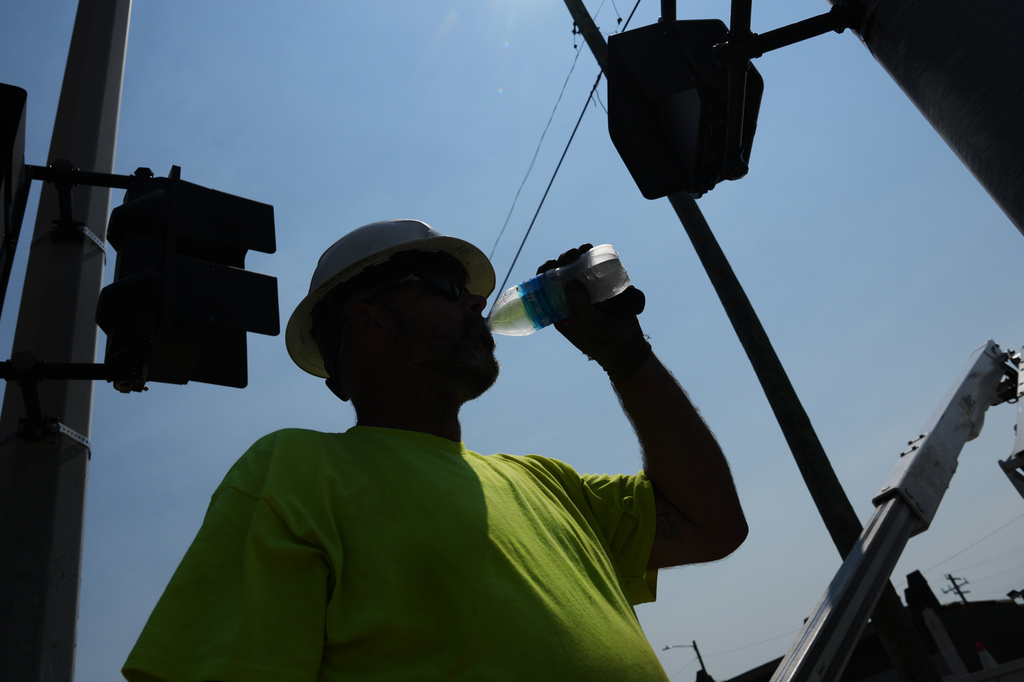 FILE - Dean Malcom drinks water while wiring street lights in extremely hot weather July 14, 2026, in Detroit. (AP Photo/Paul Sancya, File)
