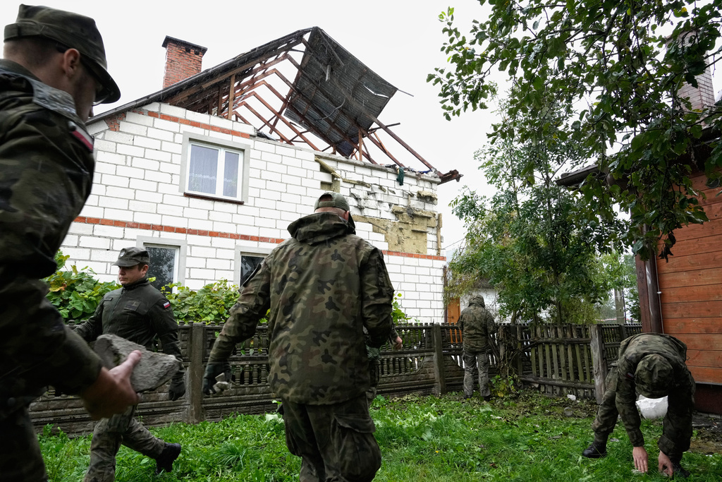 Territorial defense officers pick up debris from the destroyed roof of a house, in Wyryki, Poland, Thursday, Sept. 11, 2025, after Russian drones violated Polish airspace. (AP Photo/Czarek Sokolowski)