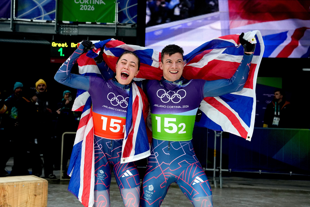Britain's gold medalists Matt Weston, right, and Britain's Tabitha Stoecker, left, celebrate at the finish during the skeleton mixed team competition at the 2026 Winter Olympics, in Cortina d'Ampezzo, Italy, Sunday, Feb. 15, 2026. (AP Photo/Alessandra Tarantino)