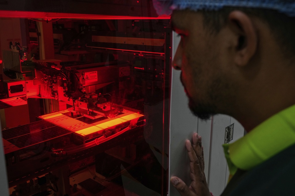 A worker monitors as single solar cells are stitched in an automated machine at a ReNew solar panel manufacturing plant on the outskirts of Jaipur, India, Thursday, Aug. 21, 2025. (AP Photo/Manish Swarup)
