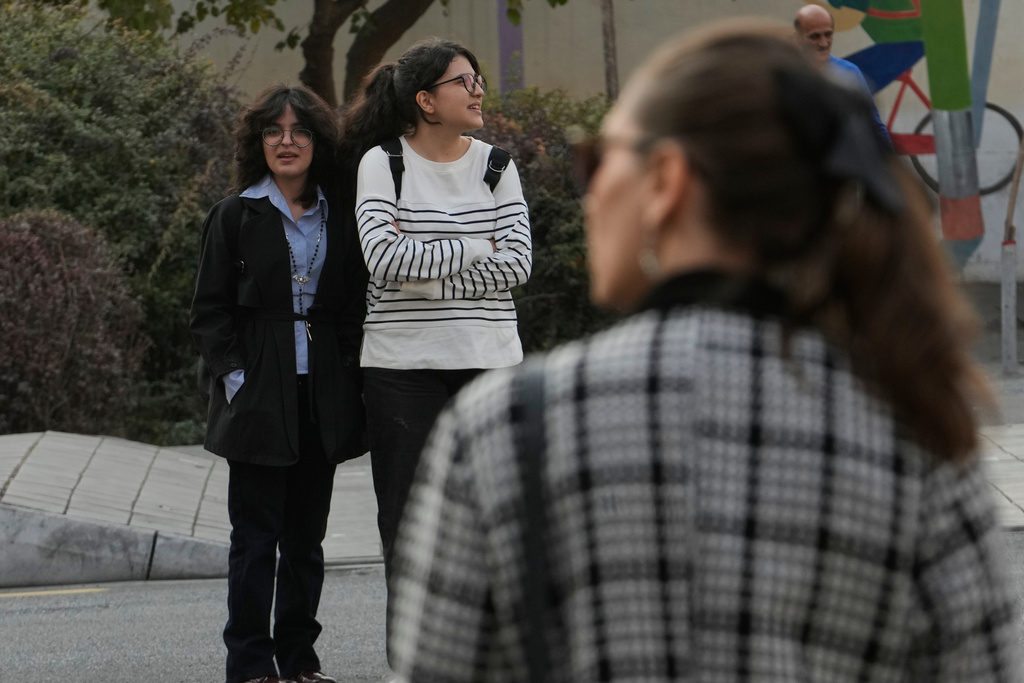 Women wait to cross an intersection in downtown Tehran, Iran, Thursday, Nov. 20, 2025. (AP Photo/Vahid Salemi)